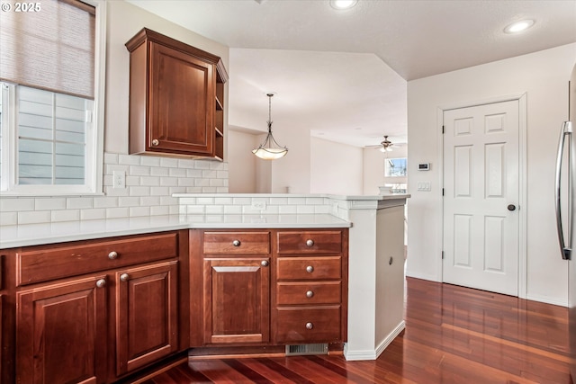 kitchen featuring pendant lighting, ceiling fan, dark hardwood / wood-style flooring, kitchen peninsula, and tasteful backsplash