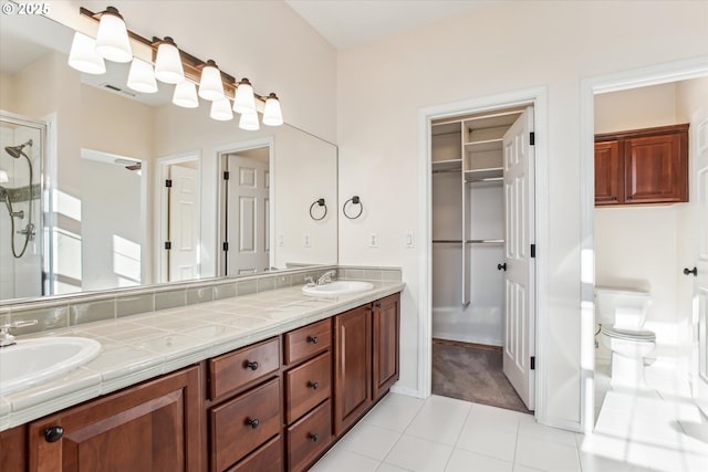 bathroom with tile patterned floors, toilet, vanity, and a shower with door