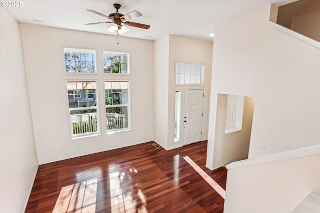 foyer featuring dark wood-type flooring, a towering ceiling, and ceiling fan