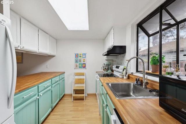 kitchen featuring a sink, white cabinets, under cabinet range hood, white appliances, and butcher block countertops
