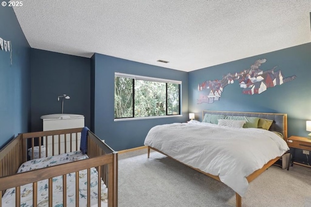 bedroom with carpet floors, a textured ceiling, visible vents, and baseboards