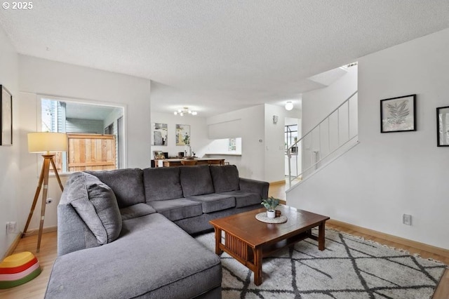 living area featuring stairs, baseboards, a textured ceiling, and wood finished floors