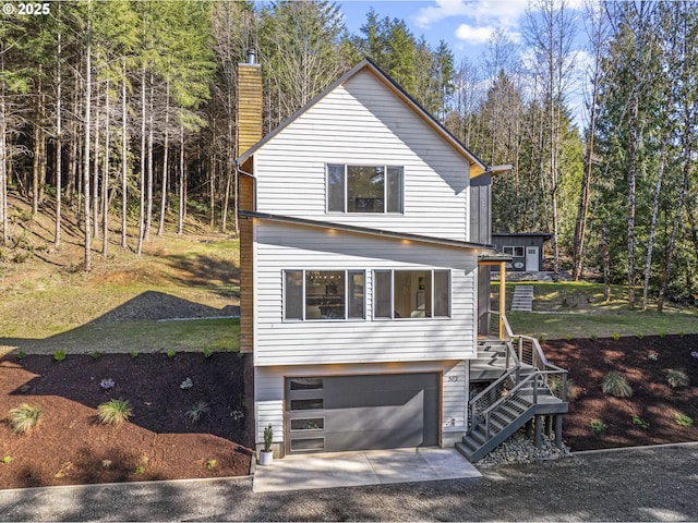 view of front of house with stairway, an attached garage, driveway, and a chimney