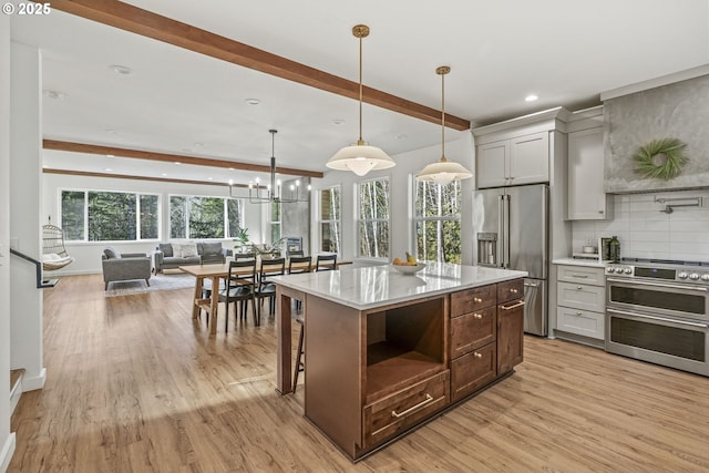 kitchen with tasteful backsplash, open floor plan, beamed ceiling, appliances with stainless steel finishes, and light wood-style floors