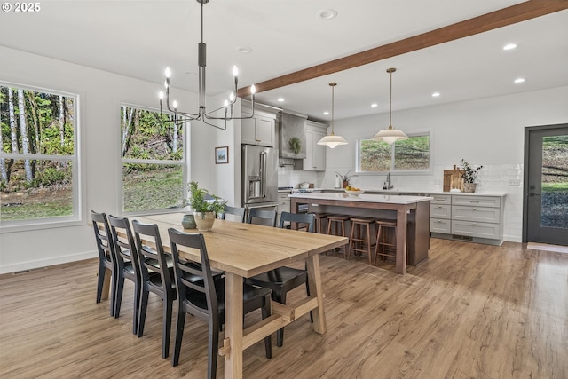 dining area featuring an inviting chandelier, recessed lighting, light wood finished floors, and beam ceiling