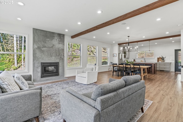 living room featuring light wood finished floors, beamed ceiling, recessed lighting, and a premium fireplace