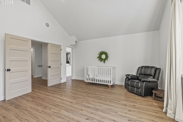 living area with visible vents, baseboards, light wood-type flooring, and high vaulted ceiling