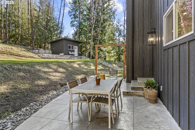 view of patio / terrace with outdoor dining space, a storage shed, and an outdoor structure