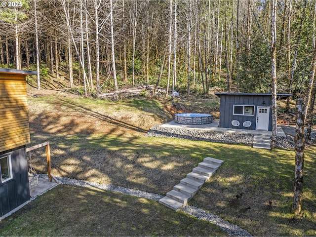 view of yard featuring an outbuilding, a fire pit, and a forest view