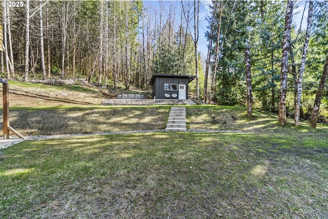 view of yard with a shed, a wooded view, and an outdoor structure