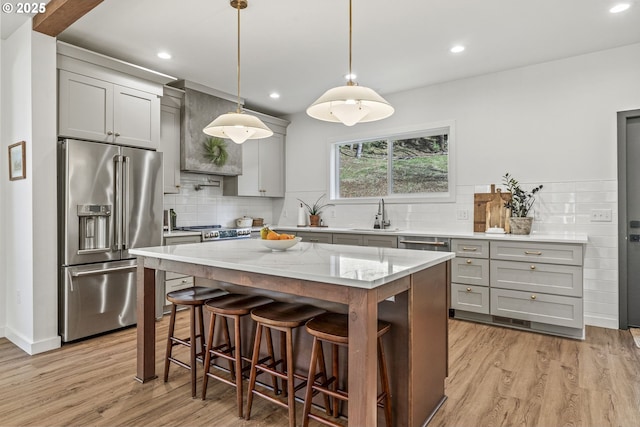 kitchen with light wood-style flooring, gray cabinets, a sink, light stone counters, and high quality fridge