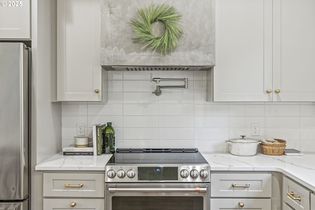 kitchen featuring tasteful backsplash, appliances with stainless steel finishes, wall chimney range hood, and light stone countertops