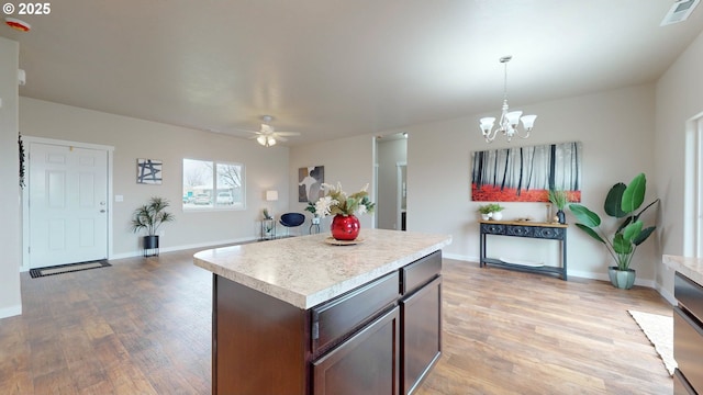 kitchen featuring decorative light fixtures, ceiling fan with notable chandelier, light hardwood / wood-style flooring, dark brown cabinetry, and a center island