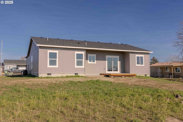 rear view of property featuring crawl space, a shingled roof, fence, and a lawn