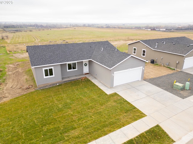 view of front of home with a garage, a front yard, and a rural view