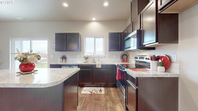 kitchen with light wood-type flooring, appliances with stainless steel finishes, dark brown cabinetry, and sink