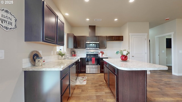 kitchen with a kitchen island, sink, dark brown cabinetry, light wood-type flooring, and stainless steel appliances