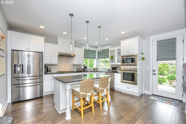 15928 Stables Pl, Oregon City, OR 97045 - kitchen with appliances with stainless steel finishes, a center island, dark countertops, a sink, and white cabinetry