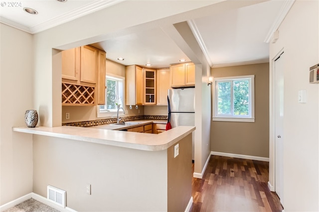 kitchen with kitchen peninsula, stainless steel refrigerator, crown molding, and sink