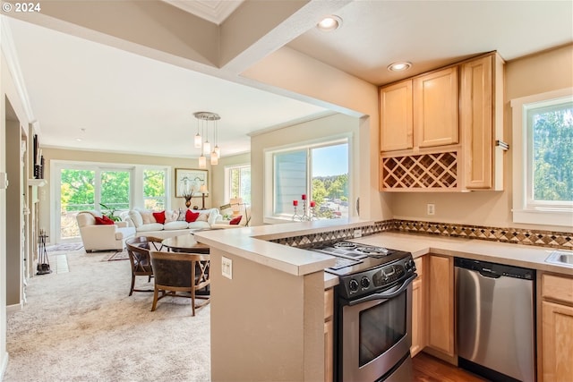 kitchen with kitchen peninsula, appliances with stainless steel finishes, light brown cabinetry, decorative light fixtures, and carpet floors