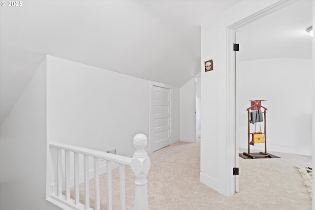 interior space featuring vaulted ceiling, carpet, and an upstairs landing