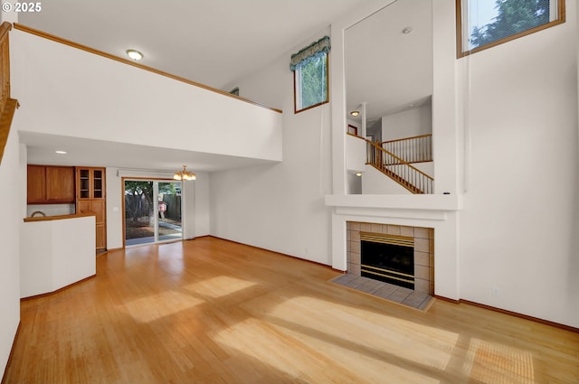4095 Eddystone Pl, Eugene, OR 97404 - unfurnished living room with a towering ceiling, a tiled fireplace, wood finished floors, a chandelier, and baseboards