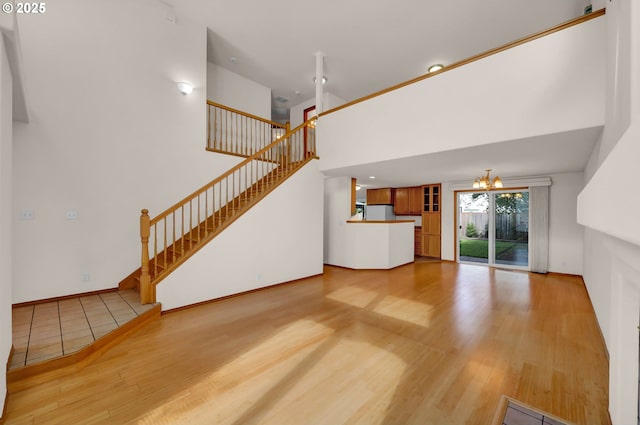 4095 Eddystone Pl, Eugene, OR 97404 - unfurnished living room with wood finished floors, a chandelier, stairs, baseboards, and a towering ceiling