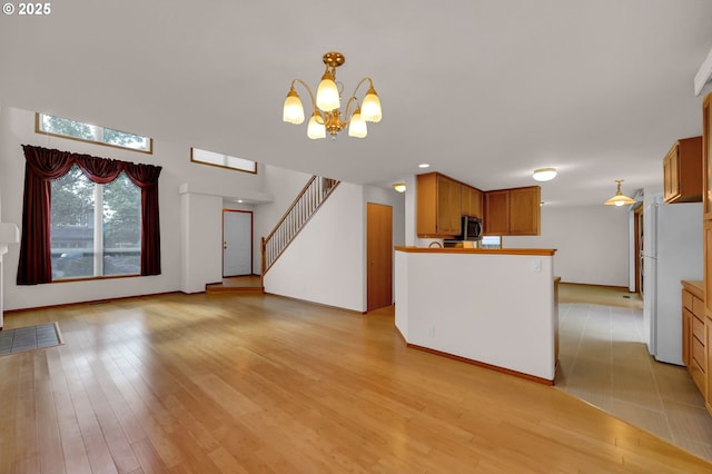4095 Eddystone Pl, Eugene, OR 97404 - kitchen with freestanding refrigerator, a chandelier, light wood-style flooring, stainless steel microwave, and brown cabinetry