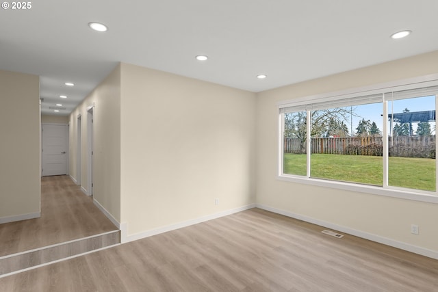 empty room with baseboards, light wood finished floors, visible vents, and recessed lighting