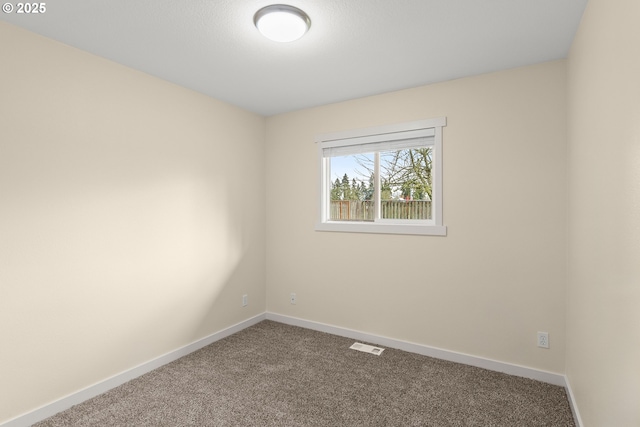 carpeted spare room with visible vents and baseboards