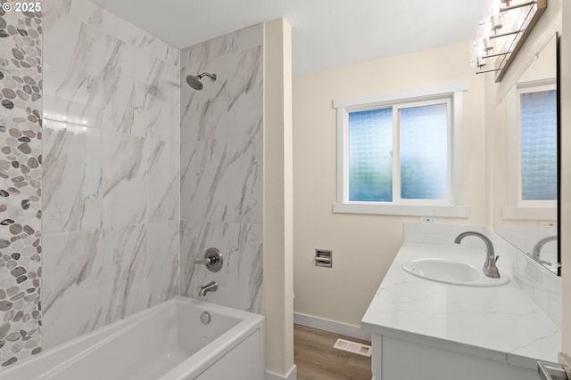 bathroom with baseboards, visible vents, wood finished floors, vanity, and washtub / shower combination