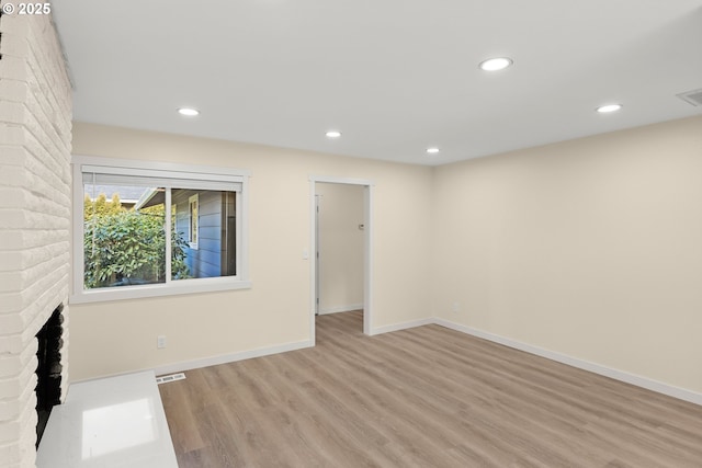 empty room with recessed lighting, a fireplace, visible vents, baseboards, and light wood-style floors