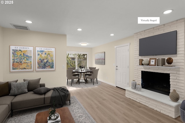 living area featuring baseboards, visible vents, wood finished floors, a fireplace, and recessed lighting