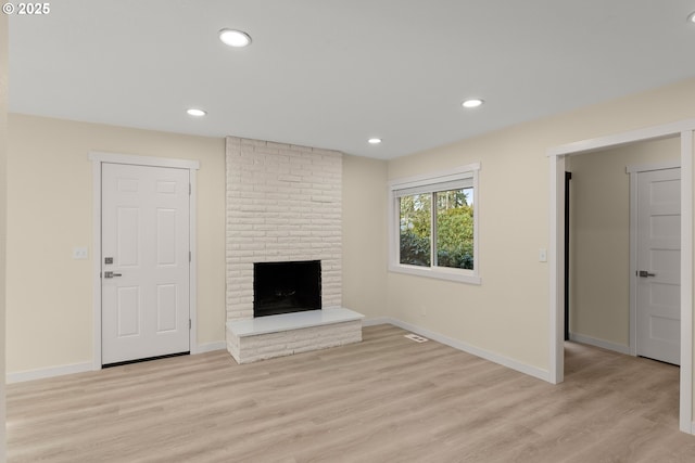 unfurnished living room featuring a brick fireplace, light wood-style floors, and recessed lighting