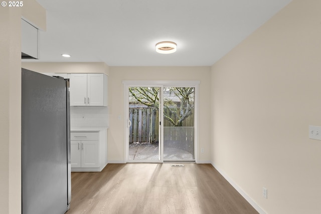 unfurnished dining area with light wood-style floors, baseboards, and recessed lighting