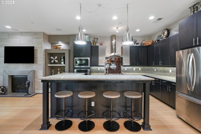 10155 SW Morrison St, Portland, OR 97225 - kitchen with appliances with stainless steel finishes, wall chimney range hood, a kitchen bar, a kitchen island, and recessed lighting