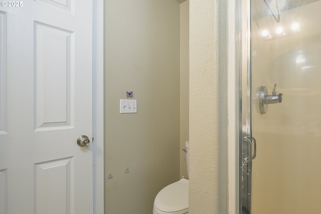 bathroom featuring walk in shower and toilet