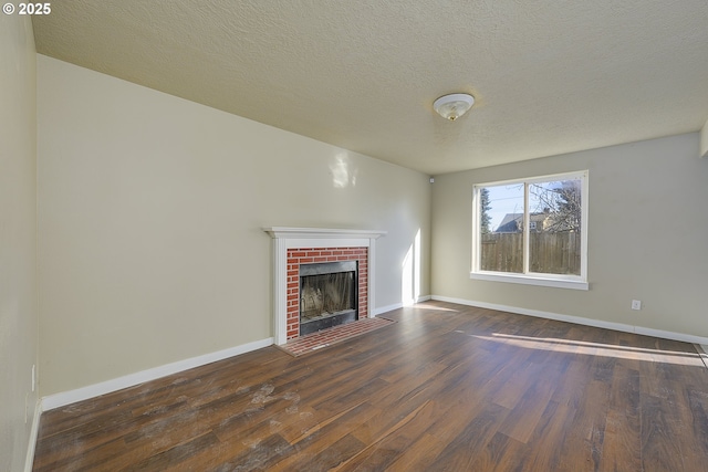 unfurnished living room featuring a brick fireplace, dark hardwood / wood-style floors, and a textured ceiling