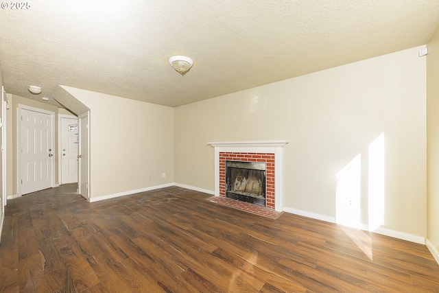 unfurnished living room with a brick fireplace, dark wood-type flooring, and a textured ceiling