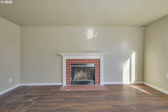 unfurnished living room featuring a brick fireplace, dark hardwood / wood-style floors, and a textured ceiling