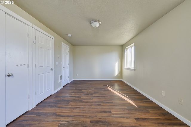 unfurnished bedroom with dark wood-type flooring and a textured ceiling