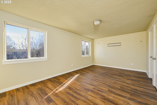 unfurnished room with dark wood-type flooring and a textured ceiling