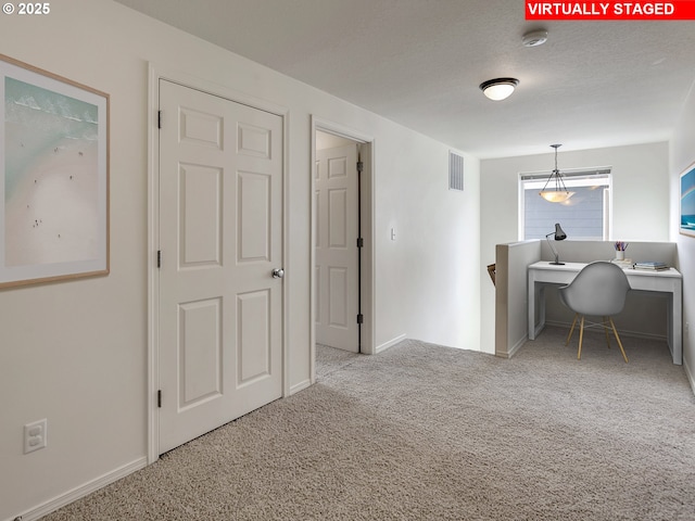 carpeted office space with visible vents, a textured ceiling, and baseboards