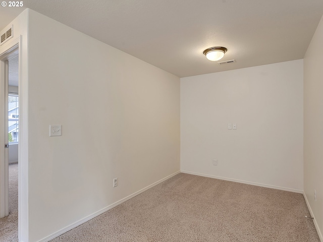 spare room featuring visible vents, light carpet, and baseboards