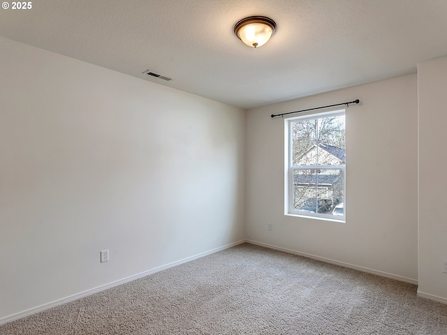 unfurnished room with a textured ceiling, baseboards, visible vents, and light carpet