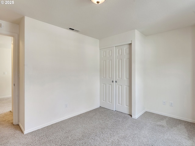 unfurnished bedroom with light carpet, visible vents, a closet, and baseboards