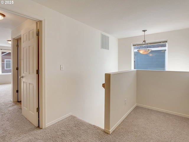 hall with light carpet, visible vents, plenty of natural light, and an upstairs landing