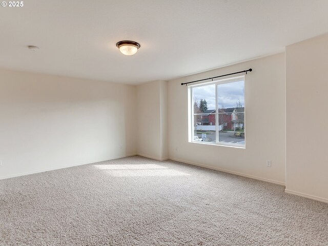 unfurnished room featuring light colored carpet and baseboards