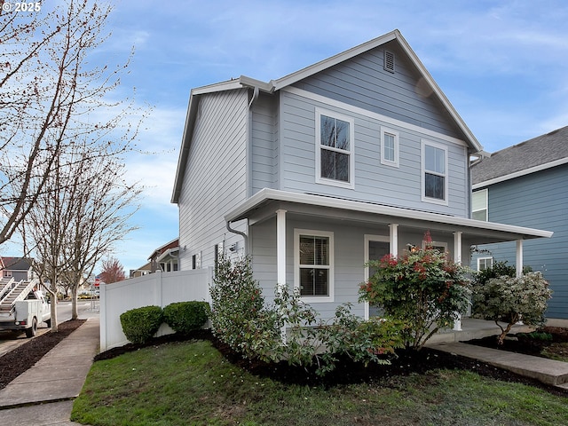 view of side of property featuring covered porch and fence