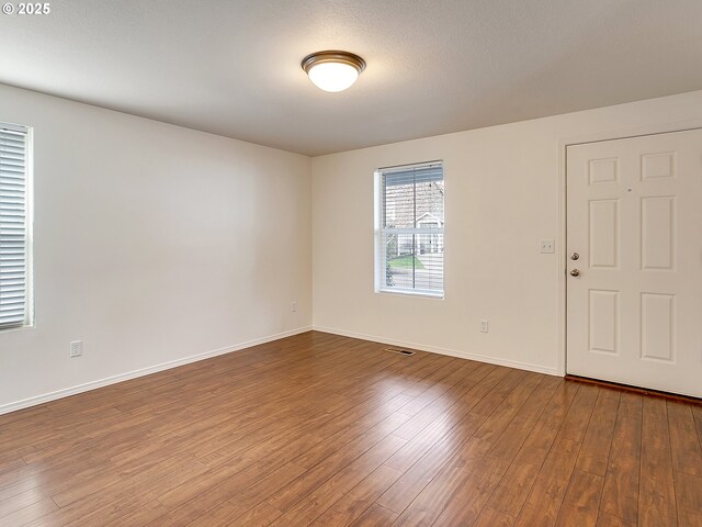 spare room with visible vents, baseboards, and wood finished floors